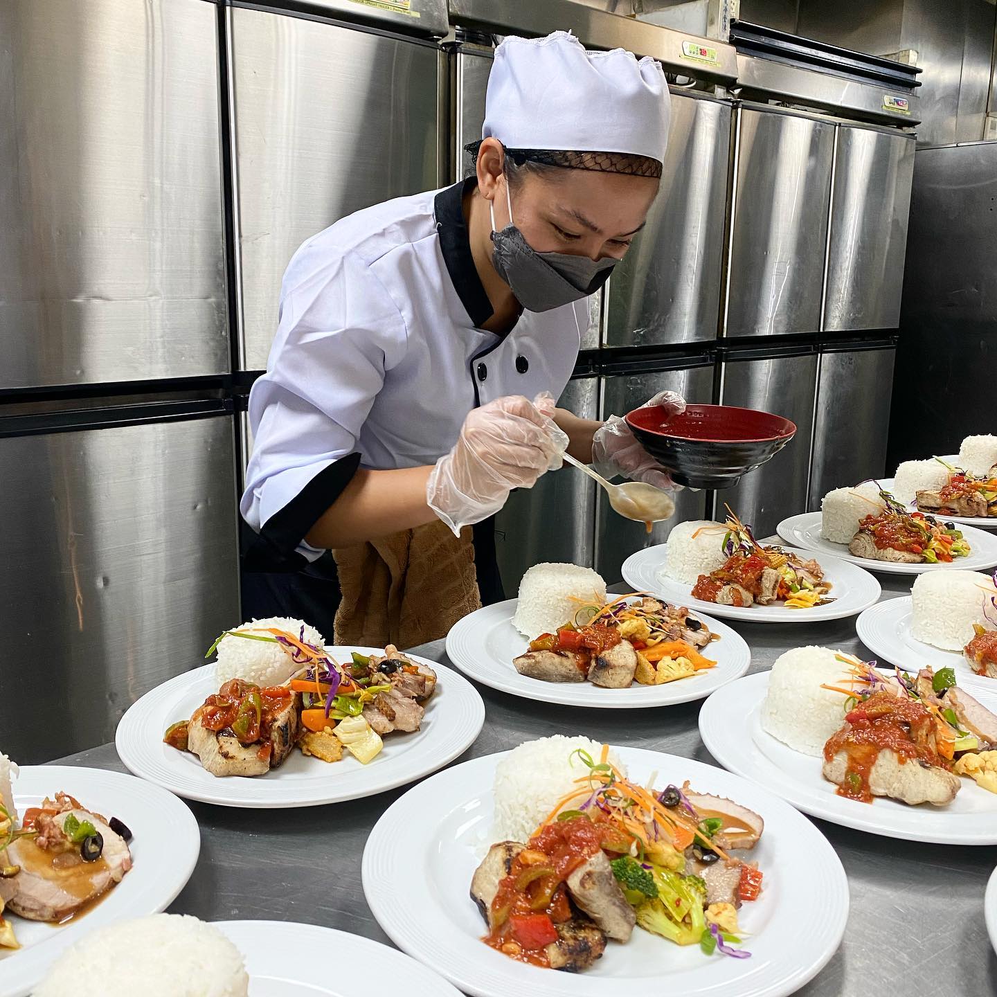Chef Abby saucing plated dishes for a catered event